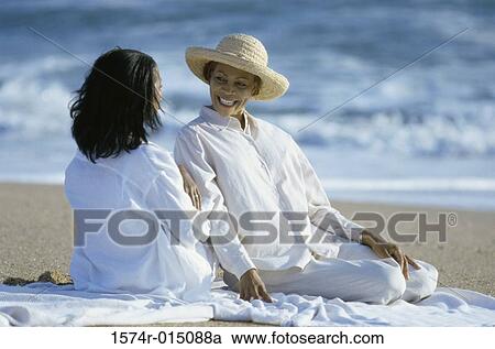 Stock Image - Rear view of a daughter talking to her mother on the beach. Fotosearch