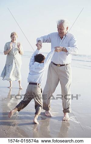 Rear view of a grandson playing with his grandfather on the beach View Large Photo Image Stock Image - Rear view of a grandson playing with his grandfather on the beach. Fotosearch