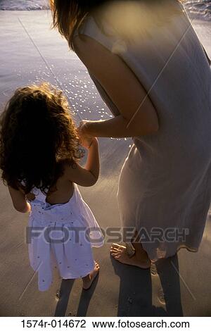 Rear view of a mother with her daughter on the beach View Large Photo Image Stock Image - Rear view of a mother with her daughter on the beach. Fotosearch