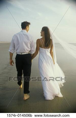 Stock Image - Rear view of a newlywed couple on the beach. Fotosearch