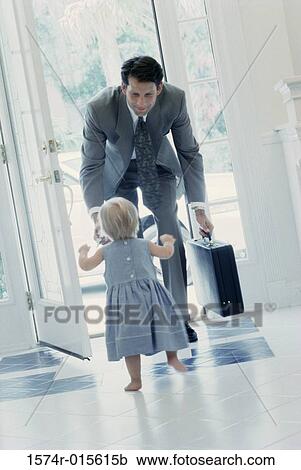 Stock Image - Rear view of girl greeting her father at the front door. Fotosearch