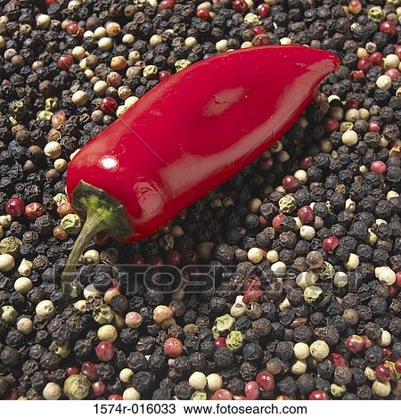 Stock Image - Red chili peppers on black peppercorns. Fotosearch