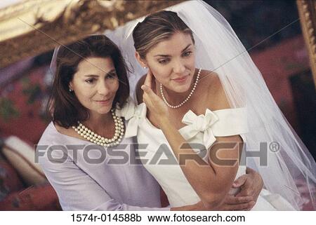 Stock Image - Reflection of a newlywed daughter standing with her mother in a mirror. Fotosearch