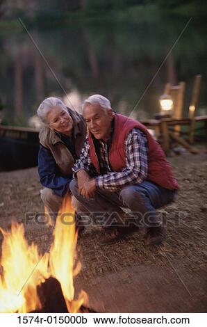 Senior couple crouching and singing near a campfire View Large Photo Image Stock Image - Senior couple crouching and singing near a campfire. Fotosearch