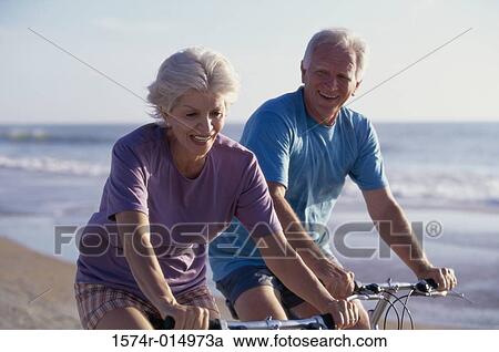 Senior couple cycling on the beach View Large Photo Image Stock Image - Senior couple cycling on the beach. Fotosearch