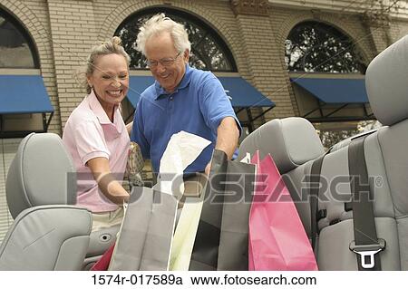 Stock Image - Senior couple putting shopping bags in their car. Fotosearch
