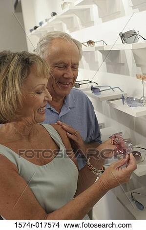 Picture - Senior couple selecting sunglasses in a store. Fotosearch