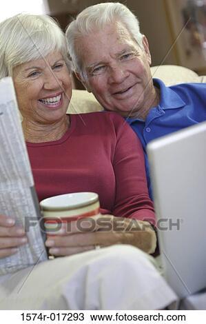 Senior couple sitting on a couch smiling View Large Photo Image Stock Image - Senior couple sitting on a couch smiling. Fotosearch