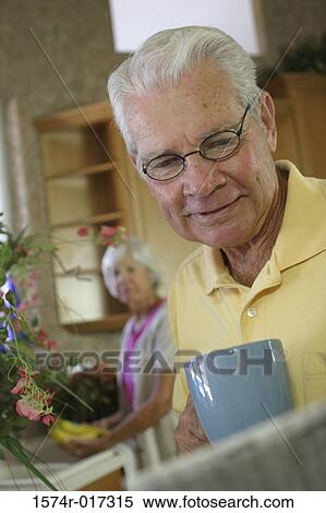 Stock Photography - Senior man holding a coffee cup reading a newspaper. Fotosearch