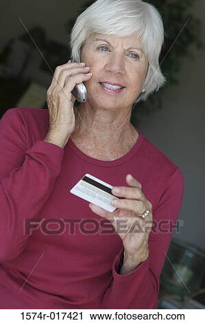 Senior woman talking on a mobile phone holding a credit card View Large Photo Image Stock Image - Senior woman talking on a mobile phone holding a credit card. Fotosearch