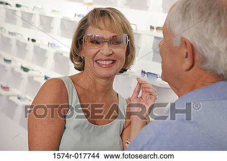 Picture - Senior woman trying on sunglasses in a store. Fotosearch