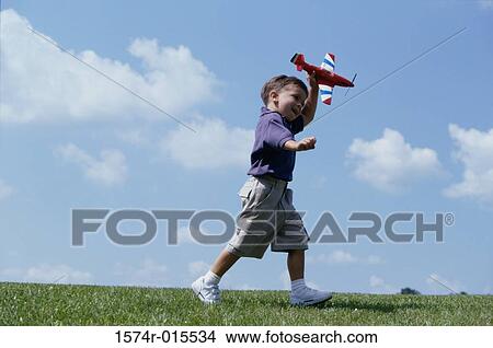 Picture - Side profile of a boy playing with a toy airplane. Fotosearch
