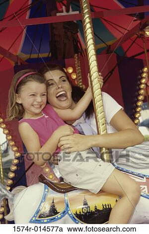 Side profile of a daughter sitting on a carousel horse with her mother standing beside her View Large Photo Image Stock Image - Side profile of a daughter sitting on a carousel horse with her mother standing beside her. Fotosearch