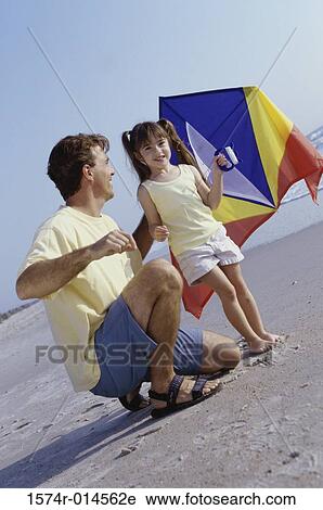 Side profile of a father helping his daughter fly a kite on the beach View Large Photo Image Stock Image - Side profile of a father helping his daughter fly a kite on the beach. Fotosearch