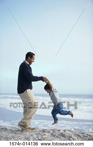 Side profile of a father swinging his son on the beach View Large Photo Image Stock Photograph - Side profile of a father swinging his son on the beach. Fotosearch