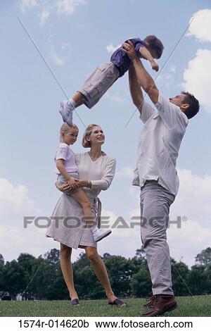 Stock Image - Side profile of a father tossing his son in the air. Fotosearch
