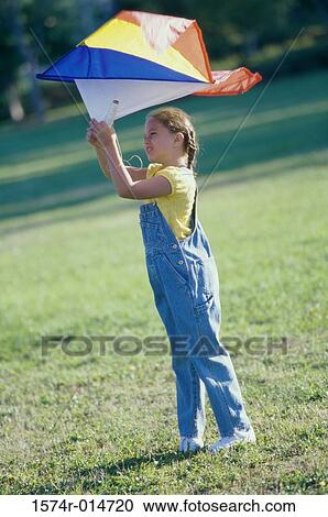 Side profile of a girl flying a kite on a lawn View Large Photo Image Stock Image - Side profile of a girl flying a kite on a lawn. Fotosearch
