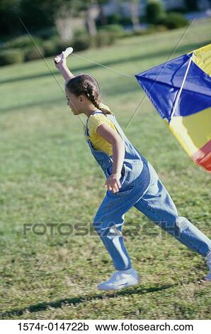 Stock Image - Side profile of a girl flying a kite. Fotosearch