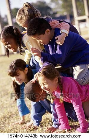 Stock Image - Side profile of a group of children making a human pyramid. Fotosearch