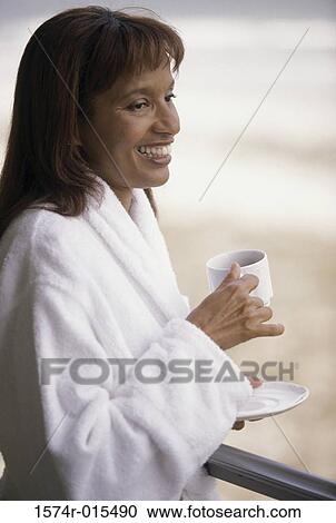 Side profile of a mid adult woman holding a cup of coffee smiling View Large Photo Image Stock Image - Side profile of a mid adult woman holding a cup of coffee smiling. Fotosearch