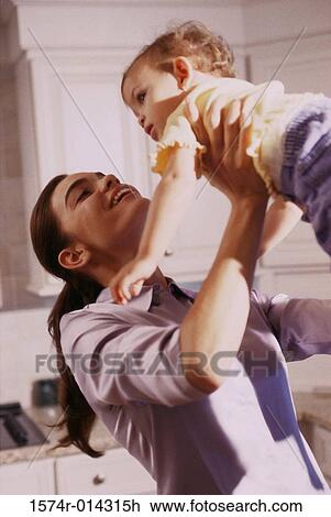 Stock Image - Side profile of a mother lifting her daughter. Fotosearch