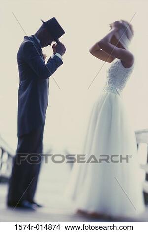 Picture - Side profile of a newlywed couple adjusting their hats. Fotosearch