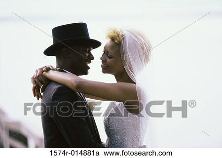 Side profile of a newlywed couple embracing each other View Large Photo Image Stock Image - Side profile of a newlywed couple embracing each other. Fotosearch