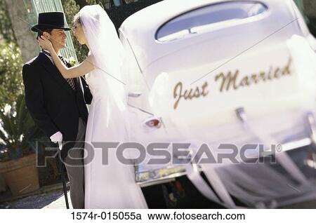 Side profile of a newlywed couple standing beside a car View Large Photo Image Stock Image - Side profile of a newlywed couple standing beside a car. Fotosearch
