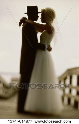 Side profile of a newlywed couple embracing each other View Large Photo Image Stock Photo - Side profile of a newlywed couple embracing each other. Fotosearch