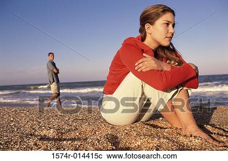 Stock Image - Side profile of a teenage girl sitting on the beach. Fotosearch