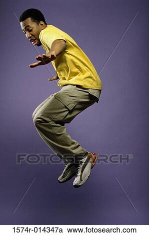 Stock Image - Side profile of a young man jumping. Fotosearch