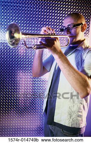 Stock Image - Side profile of a young man playing the trumpet. Fotosearch