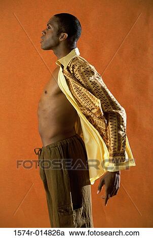 Stock Image - Side profile of a young man wearing fully unbuttoned shirt. Fotosearch
