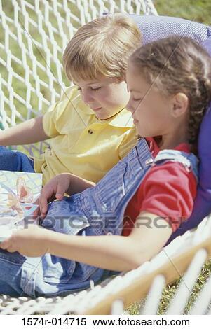 Side profile of brother and sister reading a book in a hammock View Large Photo Image Stock Photography - Side profile of brother and sister reading a book in a hammock. Fotosearch
