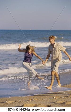 Teenage couple holding hands and walking on the beach View Large Photo Image Stock Image - Teenage couple holding hands and walking on the beach. Fotosearch