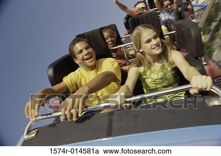 Stock Image - Teenage couple riding a rollercoaster. Fotosearch