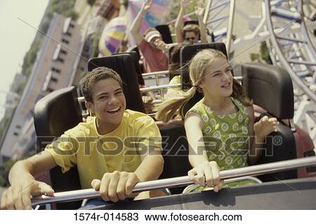 Stock Image - Teenage couple riding a rollercoaster. Fotosearch