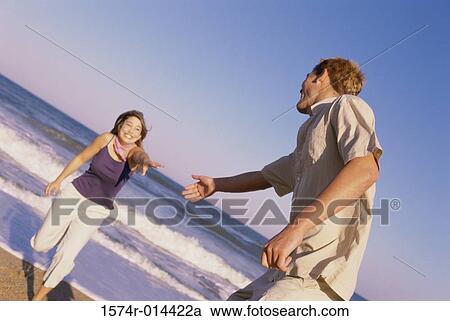 Stock Image - Teenage girl reaching out for the hand of a teenage boy. Fotosearch