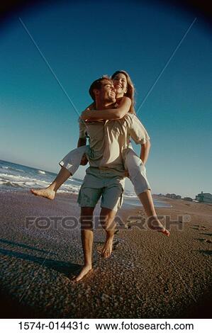 Teenage girl riding piggyback on a young man on the beach View Large Photo Image Stock Image - Teenage girl riding piggyback on a young man on the beach. Fotosearch