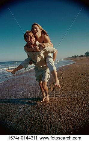 Teenage girl riding piggyback on a young man on the beach View Large Photo Image Stock Image - Teenage girl riding piggyback on a young man on the beach. Fotosearch