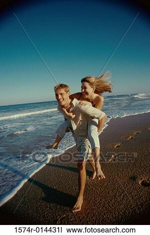 Teenage girl riding piggyback on a young man on the beach View Large Photo Image Stock Image - Teenage girl riding piggyback on a young man on the beach. Fotosearch