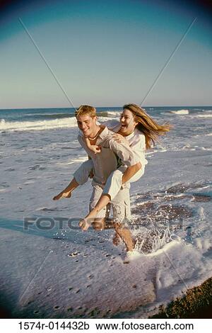 Stock Image - Teenage girl riding piggyback on a teenage boy. Fotosearch