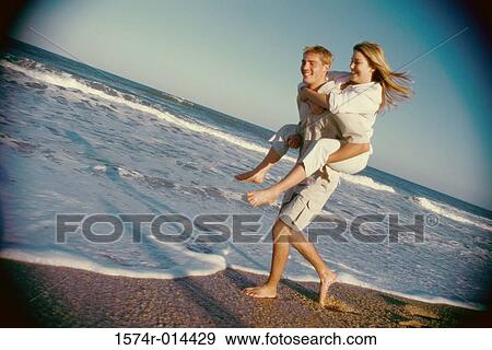Stock Photo - Teenage girl riding piggyback on a teenage boy. Fotosearch