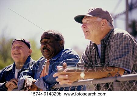 Three senior men standing against a chain-link fence View Large Photo Image Stock Image - Three senior men standing against a chain-link fence. Fotosearch