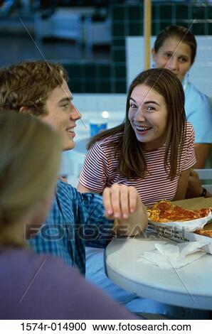 Stock Image - Three teenage girls and a teenage boy smiling in a restaurant. Fotosearch