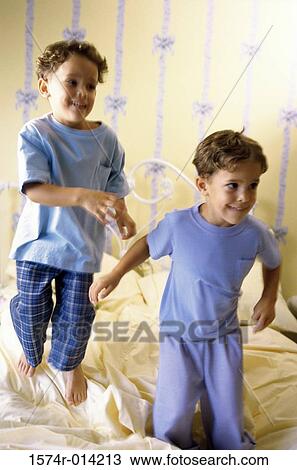 Stock Image - Two boys jumping on the bed. Fotosearch