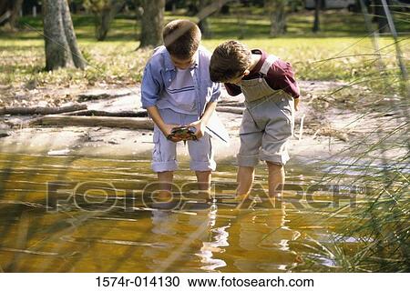 Two boys standing in water holding a turtle View Large Photo Image Stock Image - Two boys standing in water holding a turtle. Fotosearch