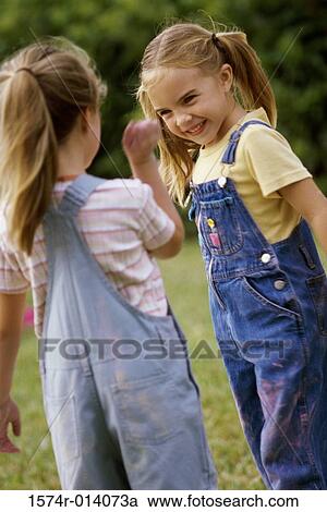 Stock Image - Two girls standing on a lawn. Fotosearch