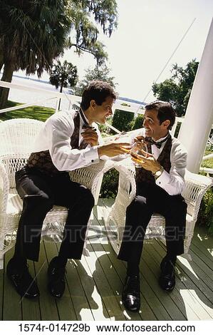 Stock Image - Two mid adult men toasting with wineglasses. Fotosearch