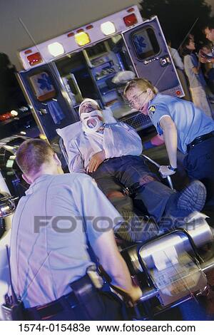 Two paramedics pushing a man on a stretcher into an ambulance View Large Photo Image Stock Image - Two paramedics pushing a man on a stretcher into an ambulance. Fotosearch